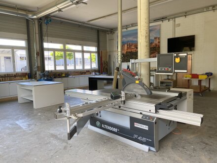 Blick in die Schreinerei mit Tischkreissäge und Werkbänken